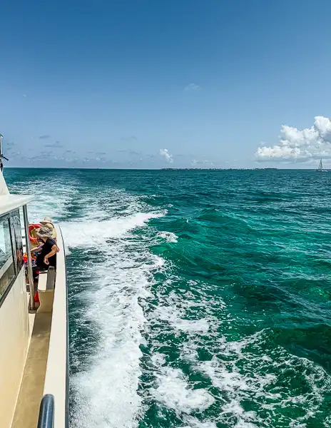 Vew from the side of a boat cruising over turquoise water on the way to the snorkeling sites in Grand Cayman.