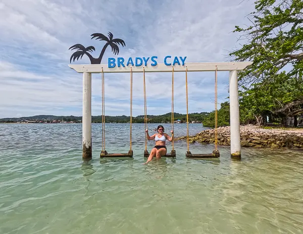 Kathy sitting on the Brady’s Cay ocean swings in Roatán, Honduras, a popular photo spot near the beach.