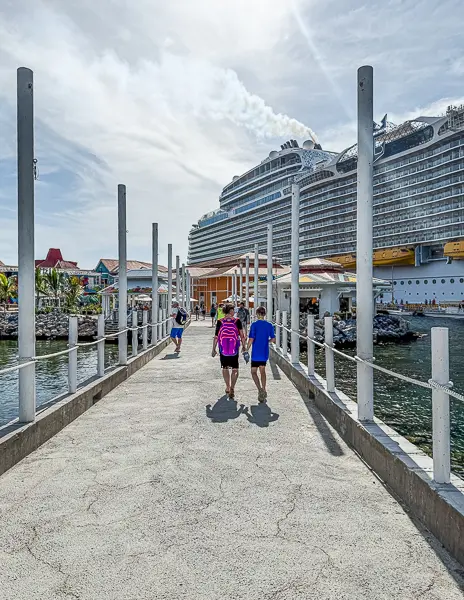 Cruise passengers walking along the pier in Roatán, Honduras, after disembarking from their ship.