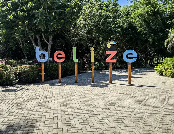 Colorful Belize sign surrounded by palm trees and greenery on Harvest Caye, Norwegian Cruise Line’s private island in Belize.