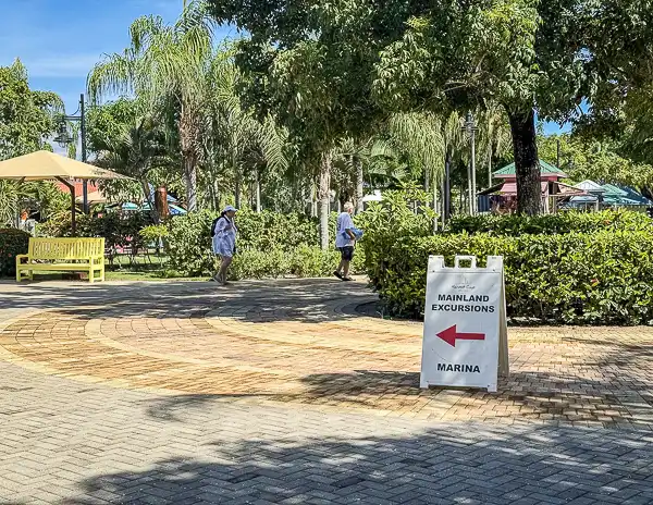 Sign on Harvest Caye, Belize pointing the way to the marina for mainland excursions and the ferry to Placencia on Norwegian Cruise Line’s private island.