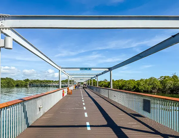Long covered pier walkway connecting the Norwegian Cruise Line ship to Harvest Caye, Belize, surrounded by mangroves and calm water.