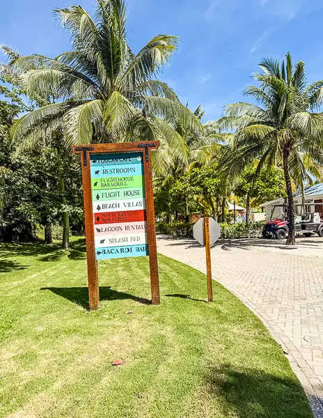 Directional sign on Harvest Caye, Belize, showing paths to the pool, Flight House, beach villas, Bacardi Bar, and other island attractions.