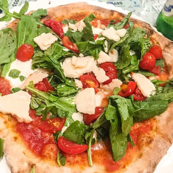 Pizza with tomato sauce, fresh tomatoes, basil and chunks of parmesan