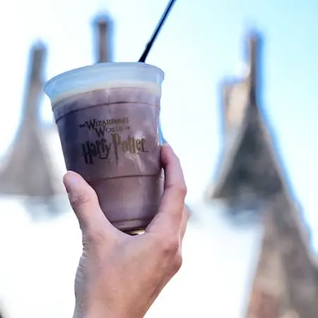 holding up a cup butterbeer at Wizarding World of Harry Potter