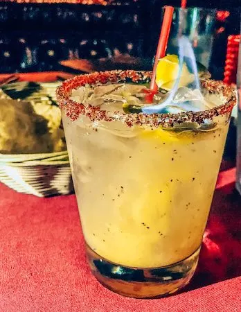Mango margarita drink with tajin salted ring and a subtle flame at the top from El Compadre Restaurant