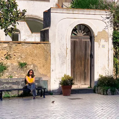 woman sitting on a bench next to an arched wooden door
