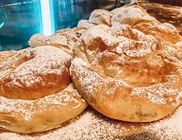 A close-up of freshly baked ensaimadas, traditional Majorcan pastries, dusted with powdered sugar at Can Joan de s’Aigo in Palma de Mallorca.