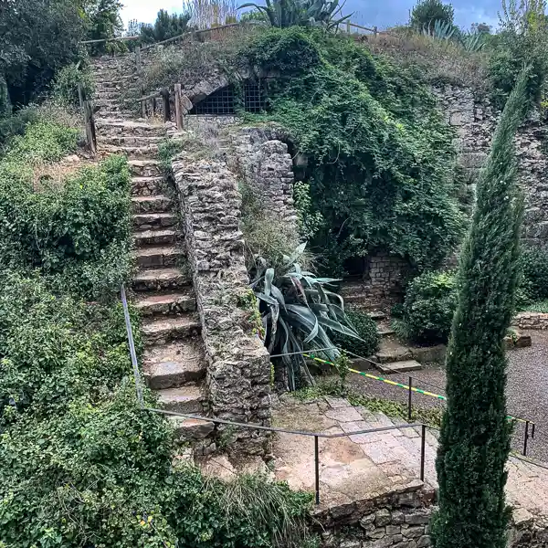 Stone steps leading up to the Girona city wall, surrounded by greenery.