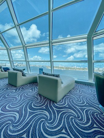 Comfy lounge chairs looking out huge windows on cruise ship