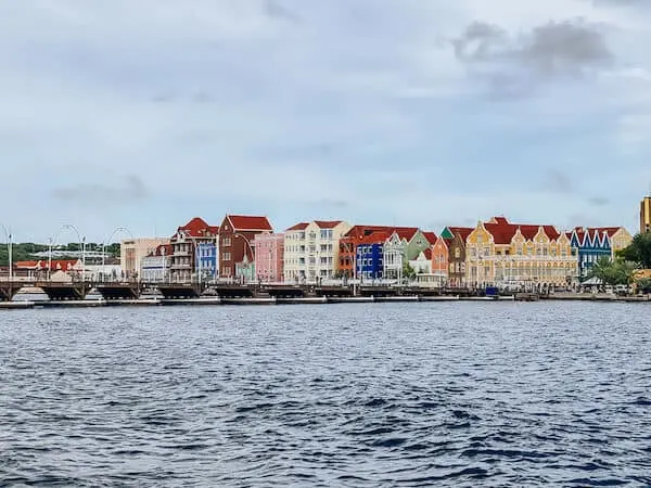 Bay of water, the Queen Emma Bridge and colorful structures behind it of Willemstad