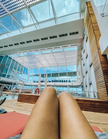 Peek of thighs and knees relaxing at a solarium pool