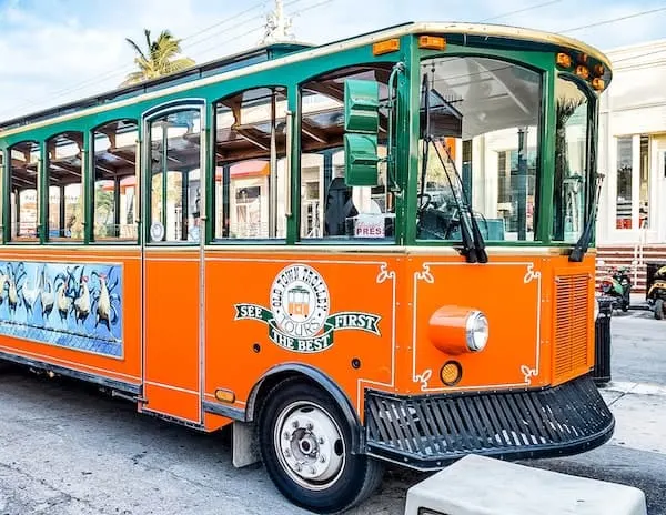 trolley, open-air windows, green top exterior, and bottom orange exterior
