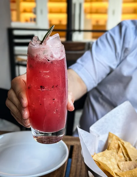 A person holding a glass of iced watermelon Aguas Frescas.