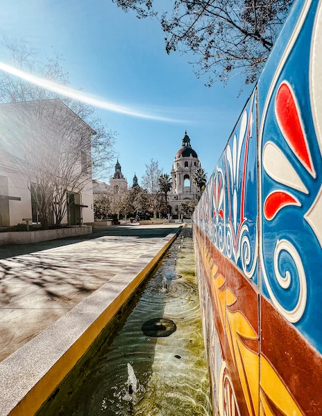 narrow pooled fountain with tiled artwork, lines leading to the view of pasadena city hall