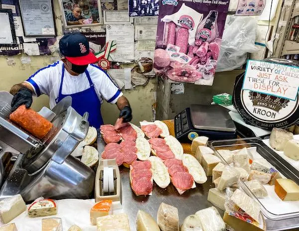 man prepping a row of sandwiches at deli counter