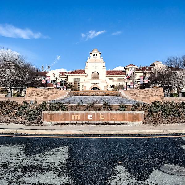 The entrance to Old Town Temecula, featuring a cascading water fountain with "Temecula" engraved on it, set against a backdrop of Spanish-style buildings and a clear blue sky.