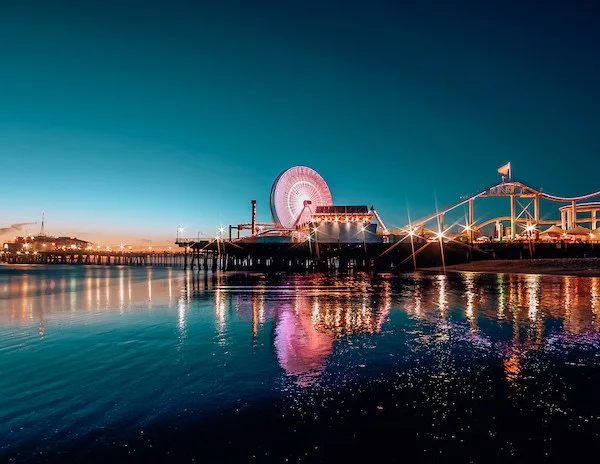 lit up pier with ferris wheel at night