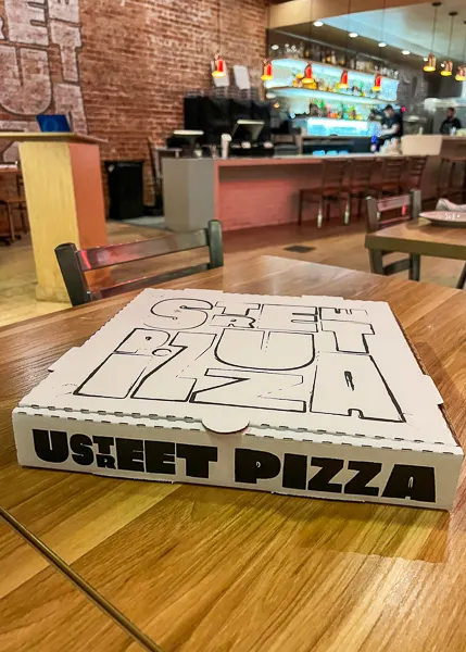 A white pizza box on a table with the text "U Street Pizza" printed on it.