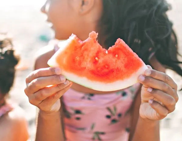 child holding and eating a watermelon