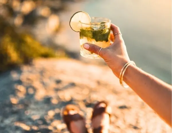 holding out a mojito with an incredible view of the shoreline and beach