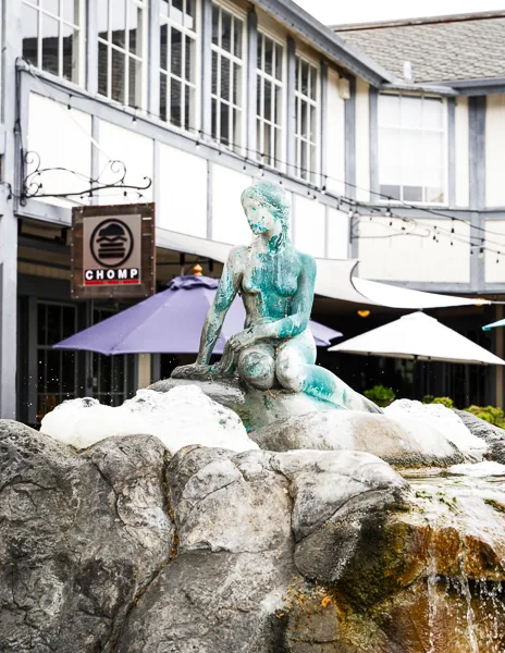A colorful fountain with a Little Mermaid statue in front of a quaint shopping area in Solvang.