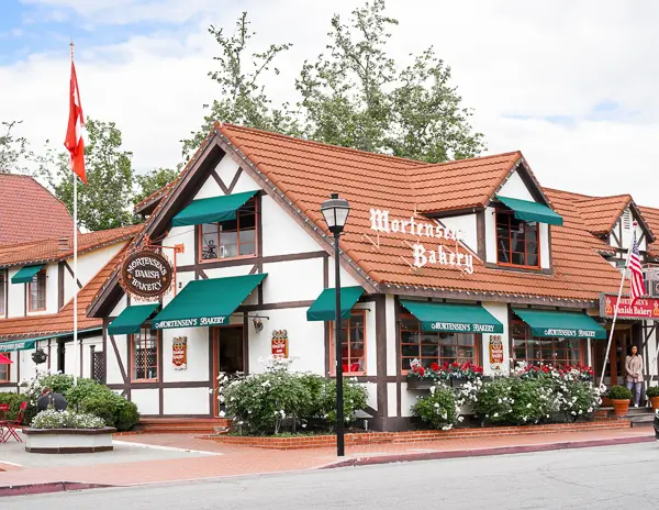 The charming façade of Mortensen’s Bakery, a Danish bakery in Solvang, showcasing traditional half-timbered architecture and blooming flower boxes.