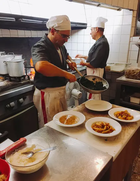 hefs in a bustling kitchen at Trattoria Sostanza in Florence, Italy, skillfully preparing traditional Tuscan dishes with a focus and craftsmanship that speaks to the heart of Italian cooking.