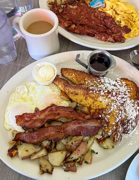 breakfast plate of eggs, bacon, potatoes, french toast