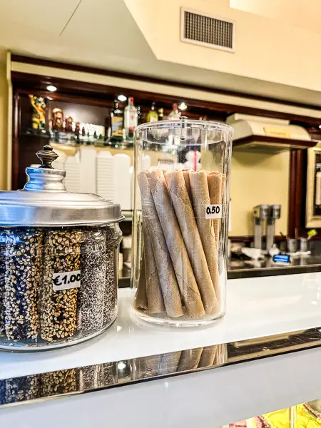 A glass jar on the counter of Gelateria dei Neri, filled with crisp rolled cookies priced at €0.50 each.
