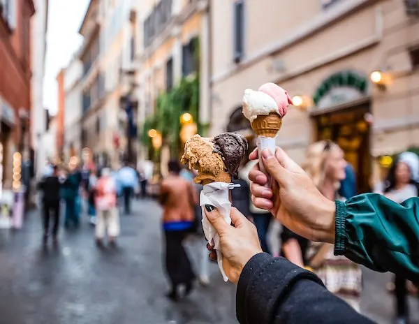 holding up two gelato cones in the busy streets of florence