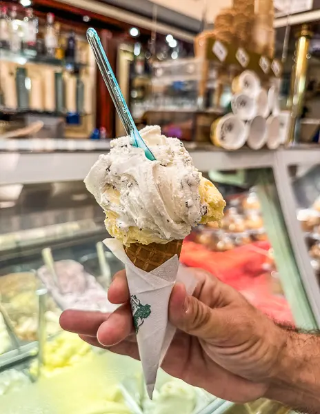 A hand holding a gelato cone from Gelateria dei Neri, with creamy, chunky scoops ready to be enjoyed.