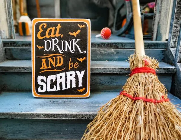 eat, drink and be scary sign and a wicker broom