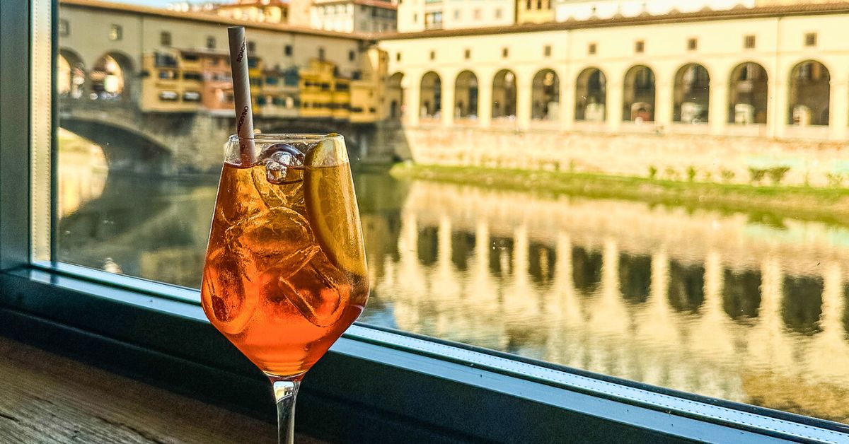 featured blog image for places to eat in florence, a aperol spritz with a view of the ponte vecchio and arno river