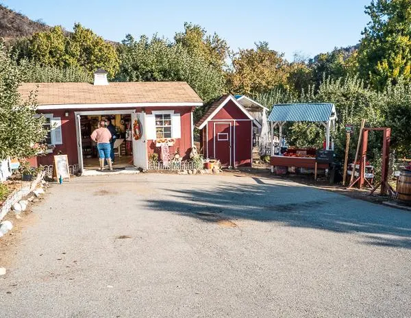 Entrance view of Willowbrook Apple Farm with a small red building and farm stand.