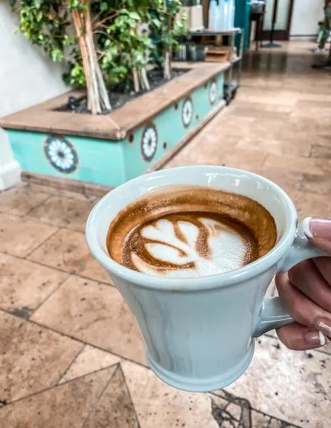 a spanish latte in a white ceramic mug with beautiful coffee art on top