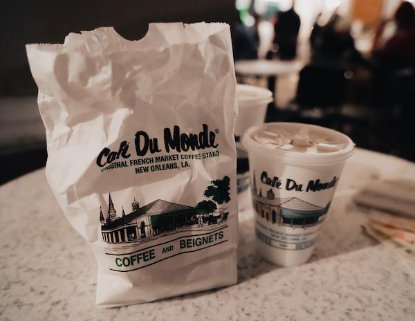 a bag of beignets and coffee cup from cafe du monde