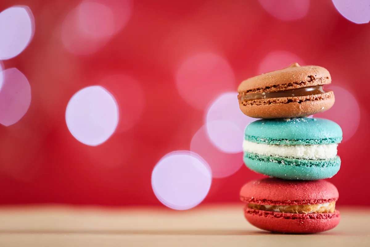 featured blog image | foodie gifts | three colorful macarons sitting atop of each other against a red backround with lights