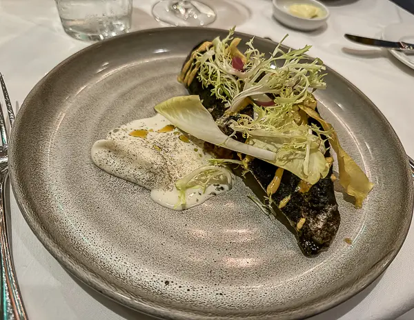 Blackened redfish fillet topped with greens and served with a light foam sauce at Brennan’s Restaurant in New Orleans.
