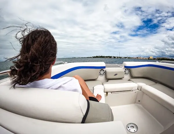 A woman (kathy) enjoying a boat charter ride in Islamorada, Florida, seated at the front of the vessel with her hair blowing in the breeze and scenic water views ahead.