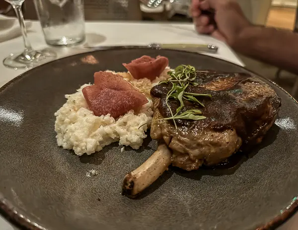 Bone-in ribeye steak with creamy risotto and poached pear slices at Brennan’s Restaurant in New Orleans.