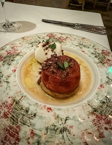 Heirloom tomato salad with burrata and olive tapenade, elegantly plated at Brennan’s Restaurant in New Orleans.