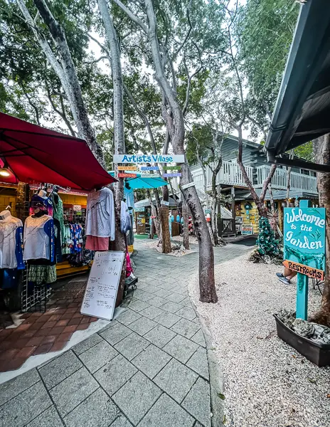 Rain Barrel Village in Islamorada, Florida, featuring boutique shops, colorful signs, and a charming outdoor artists’ market surrounded by trees.