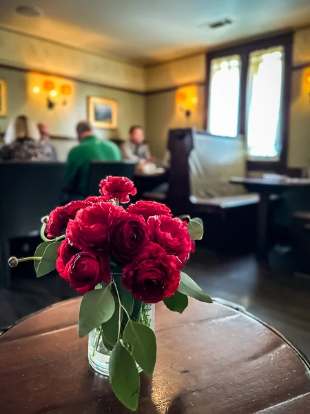 roses on a table overlooking diners inside the raymond in pasadena