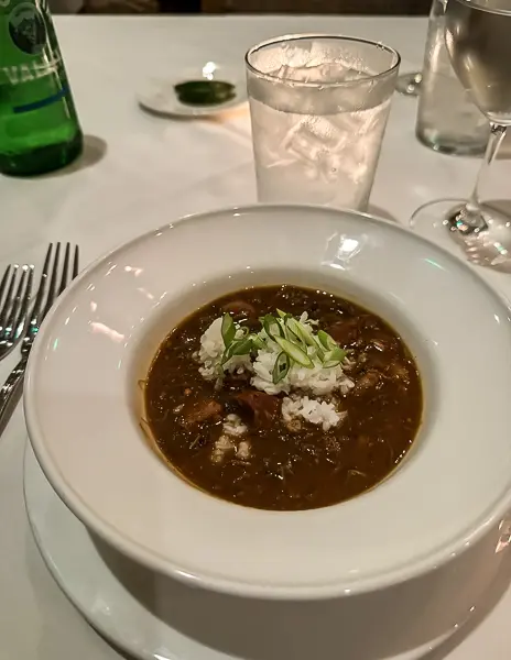 Seafood gumbo topped with rice and scallions, served in a white bowl at Brennan’s Restaurant in New Orleans.