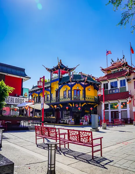 Colorful buildings and red benches in Chinatown Central Plaza in Downtown LA on a sunny day.
