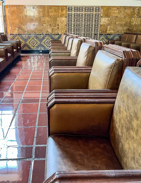 Row of vintage leather chairs inside Union Station in Downtown LA, with tiled floors and detailed wall decor in the background.