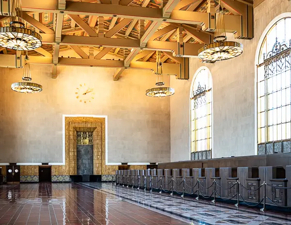 Wide view of the old ticketing counters inside Union Station in Downtown LA, with art deco details, arched windows, and a vintage clock on the far wall.