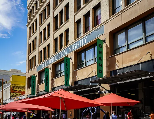 Exterior of Grand Central Market in Downtown LA with red umbrellas and a sign reading "Open Until 10 P.M. Nightly"