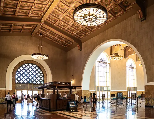 Interior of Union Station’s main hall in Downtown LA, featuring arched windows, decorative ceilings, and the central information booth.